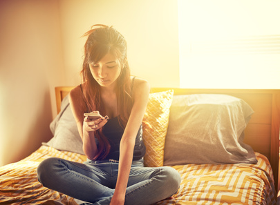 Girl-using-her-smartphone-in-her-bedroom.jpg